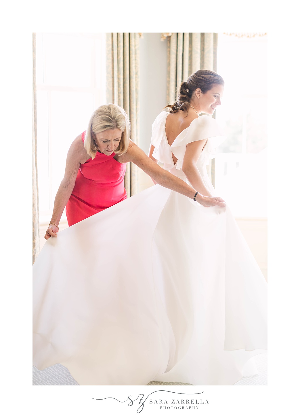 mother of the bride helps bride with wedding dress