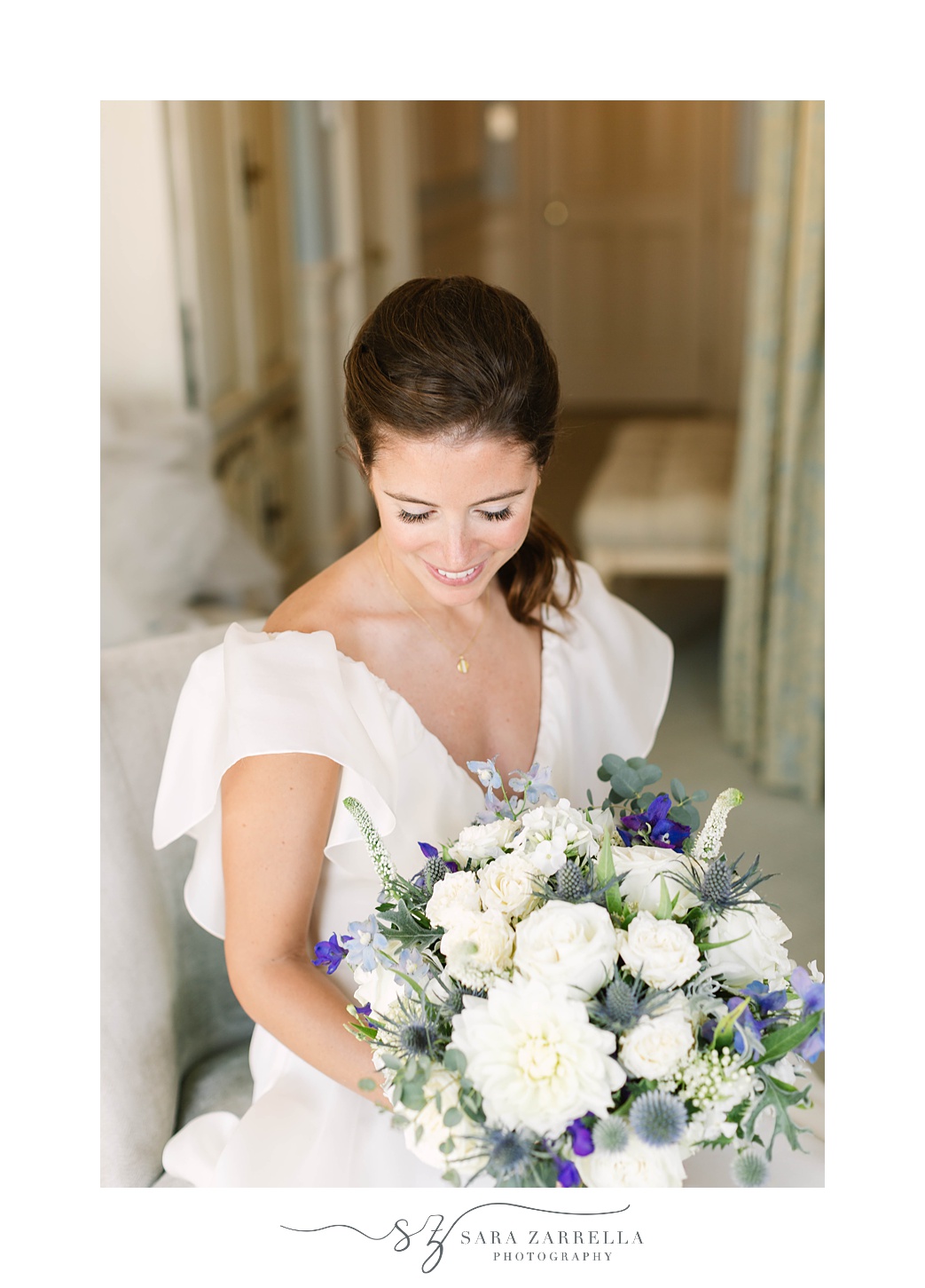 bride in ponytail looks down at bouquet of white flowers