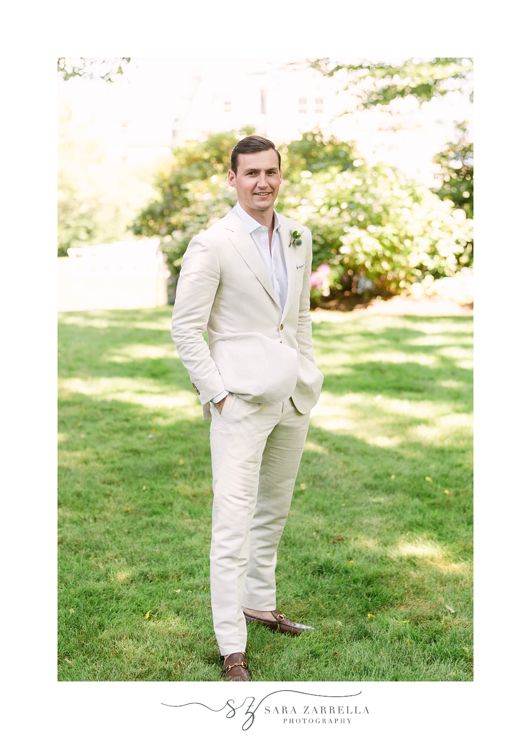 groom poses in tan suit at The Chanler at Cliff Walk
