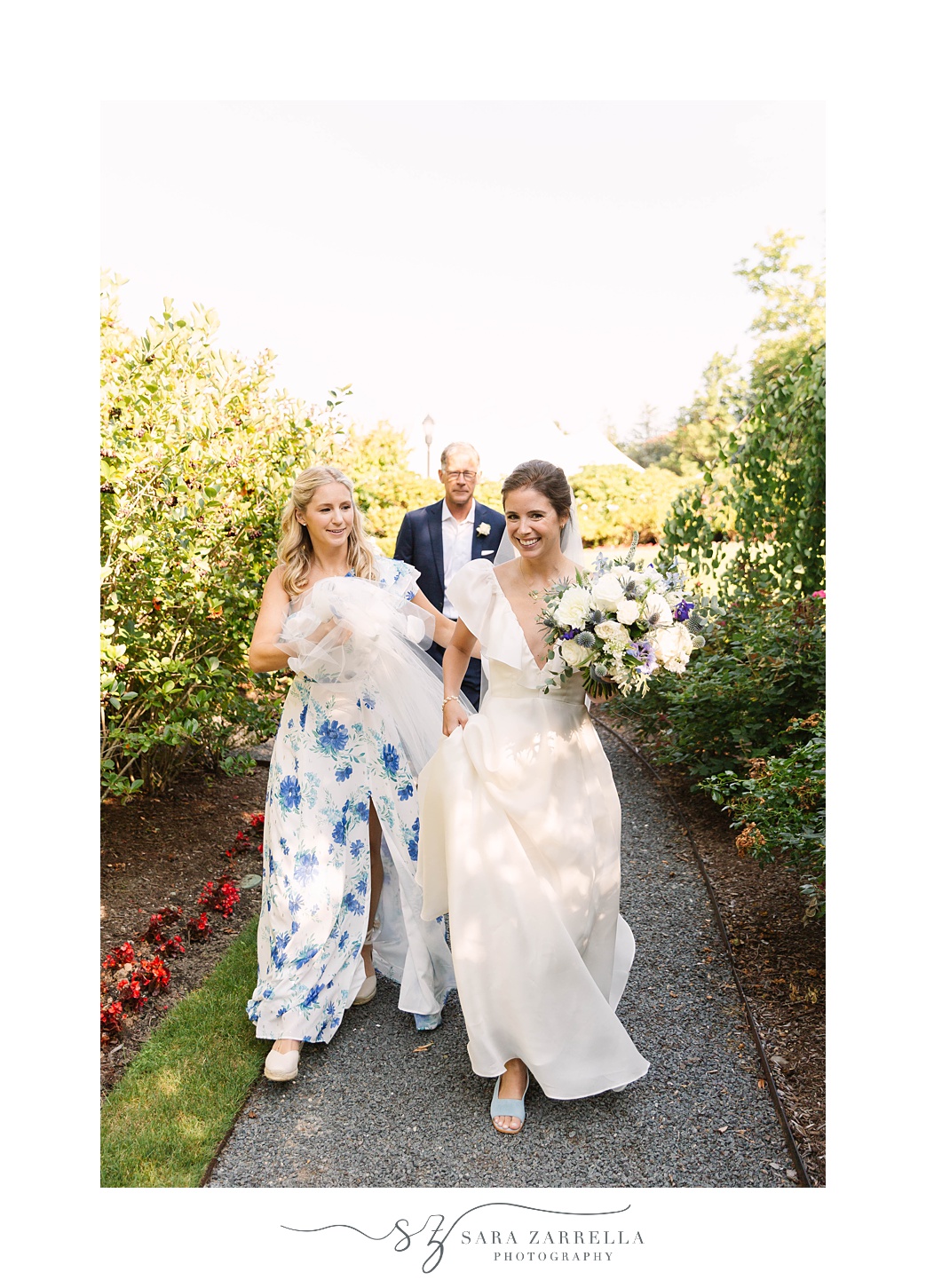 sister helps bride carry wedding dress