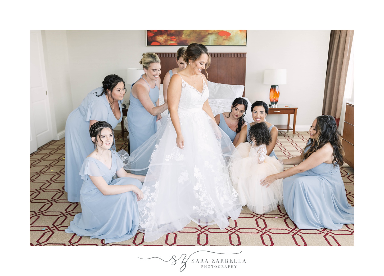 bridesmaids help bride with wedding gown