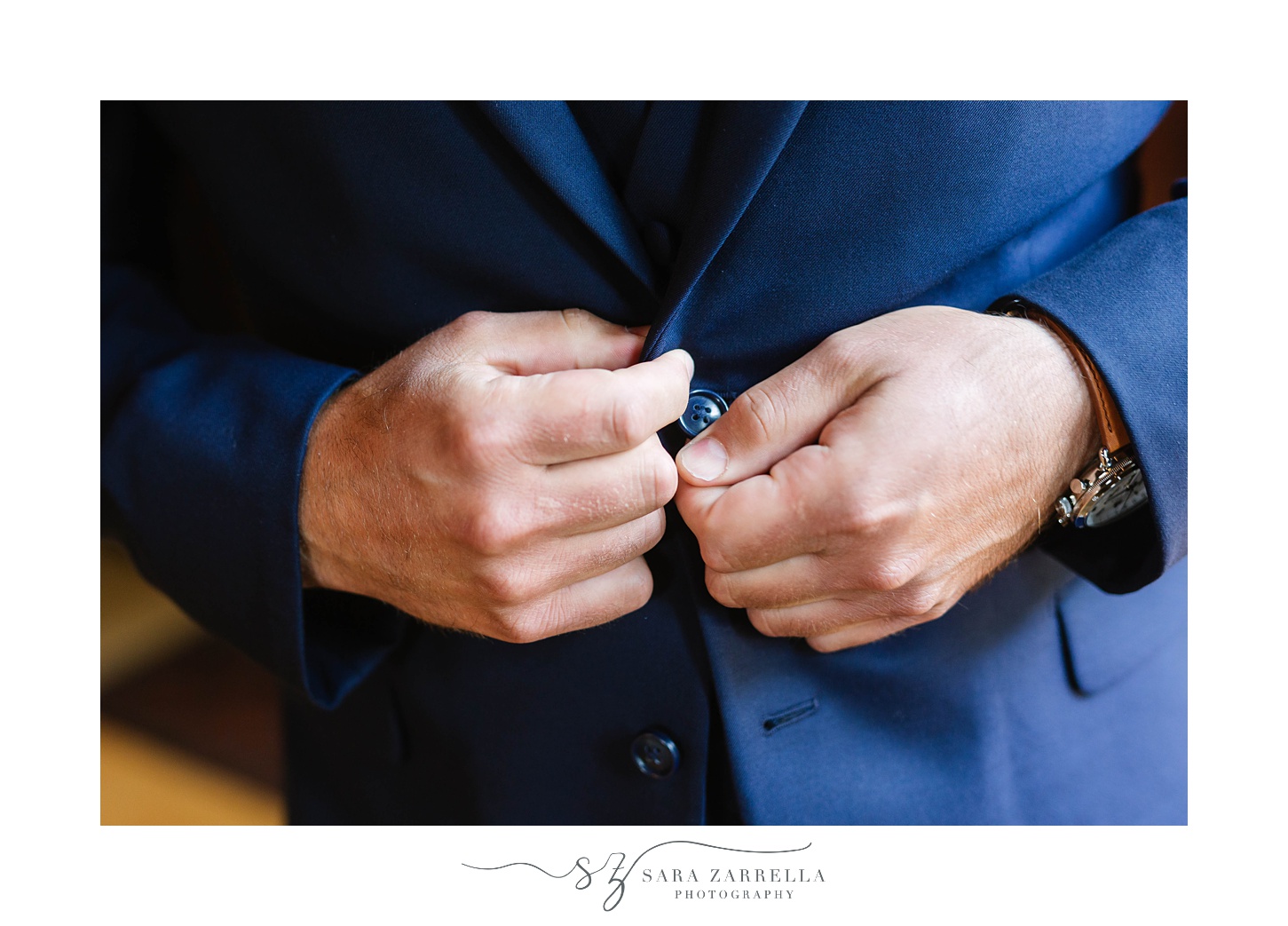 groom adjusts buttons on navy jacket before RI wedding