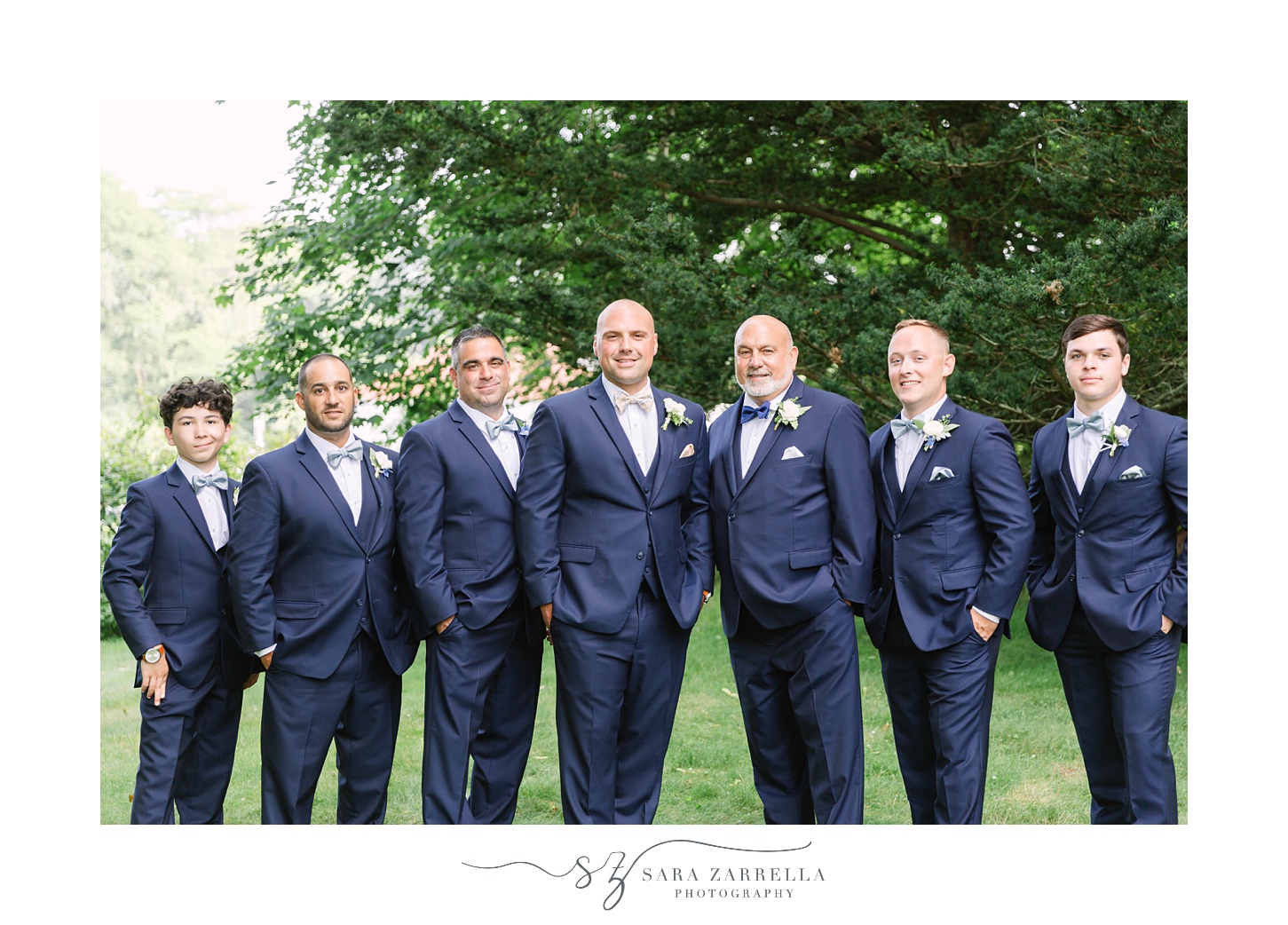 groom and groomsmen in navy suits pose at Castle Hill Inn