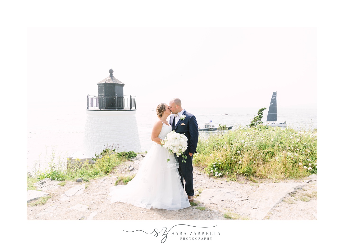 bride and groom kiss by white lighthouse in Rhode Island