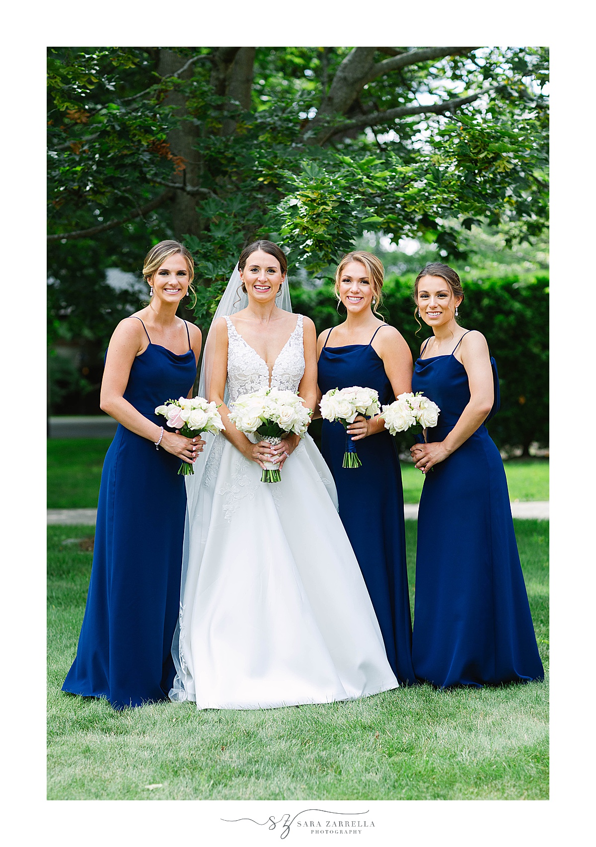 three bridesmaids in navy gowns stand with bride