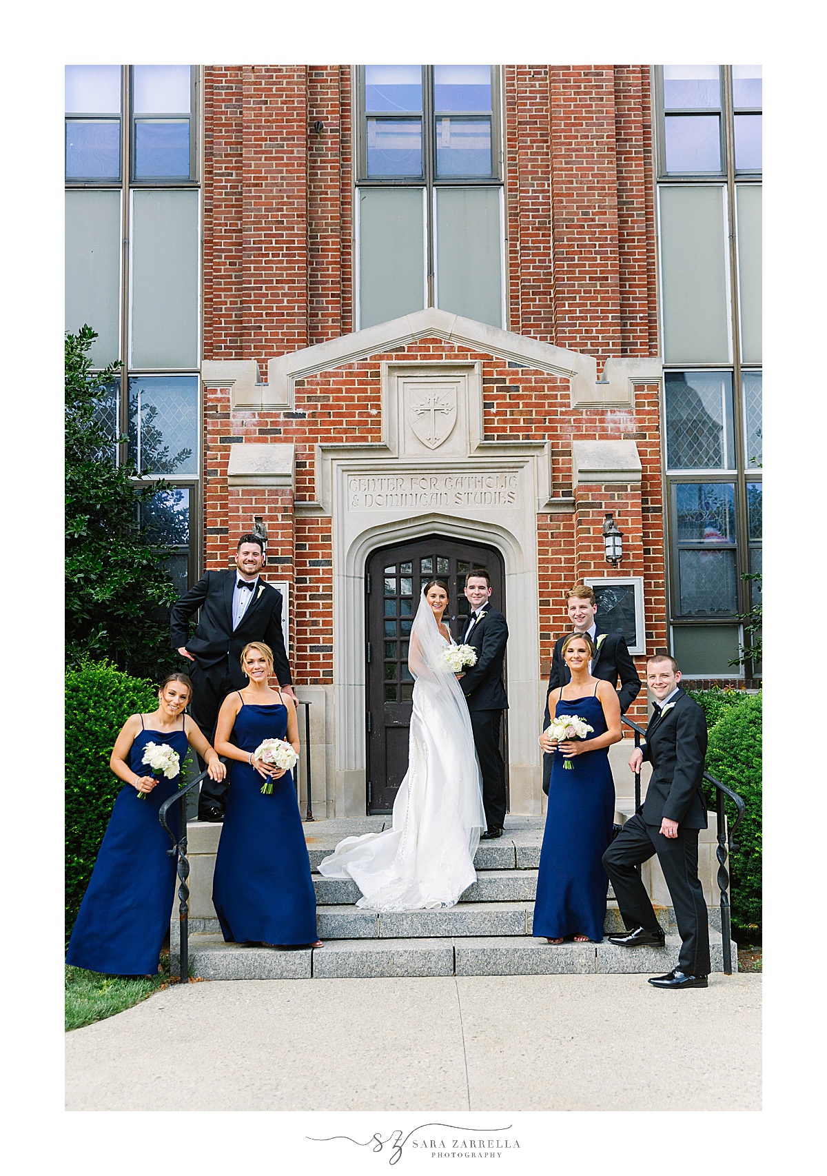 newlyweds pose with bridal party on steps of building at Providence College