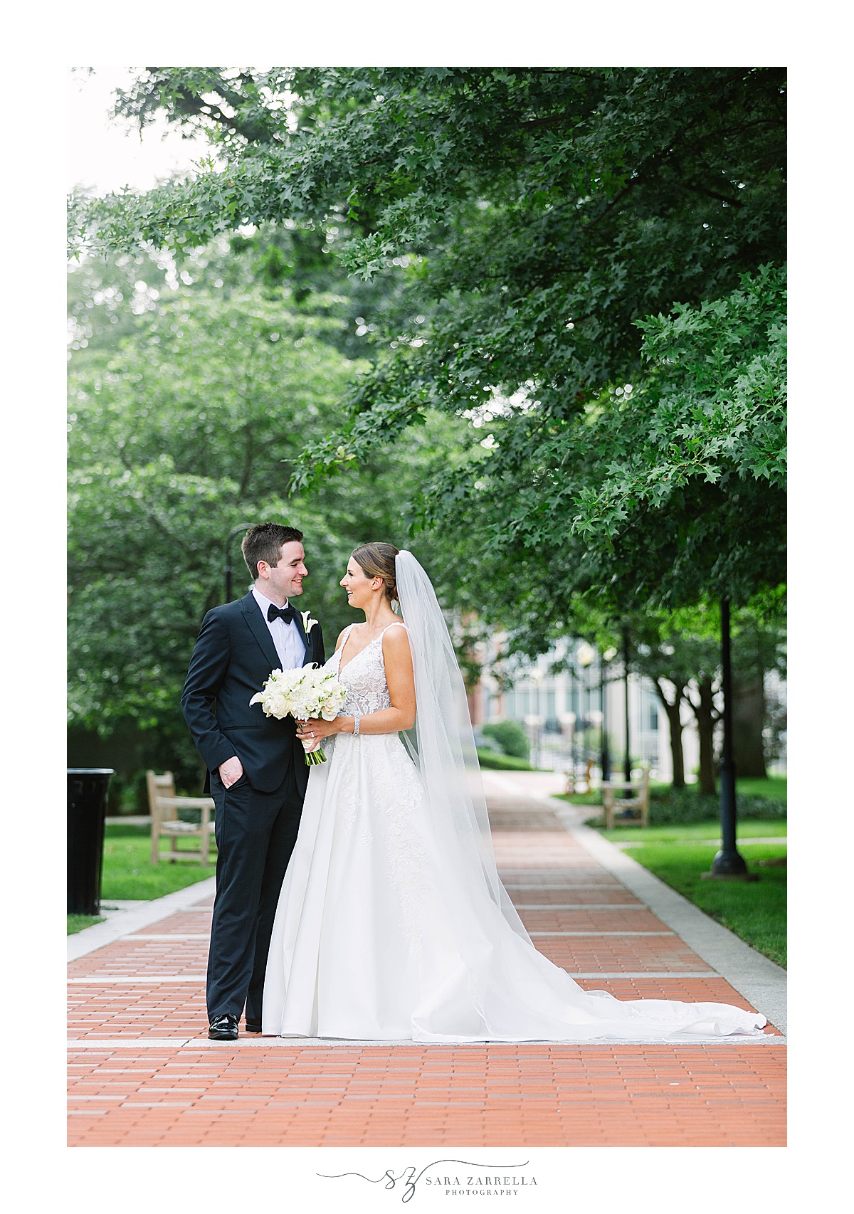 bride and groom stand together on sidewalk at Providence College