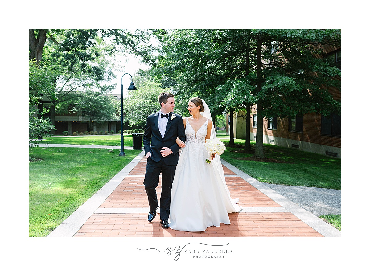 bride and groom walk through Providence College campus 
