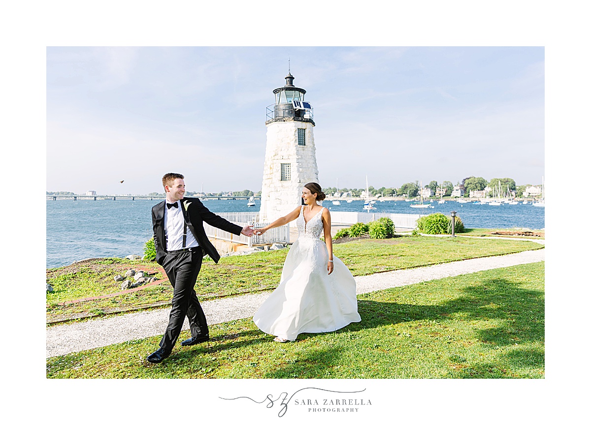 bride and groom walk by lighthouse near Gurney’s Newport Resort