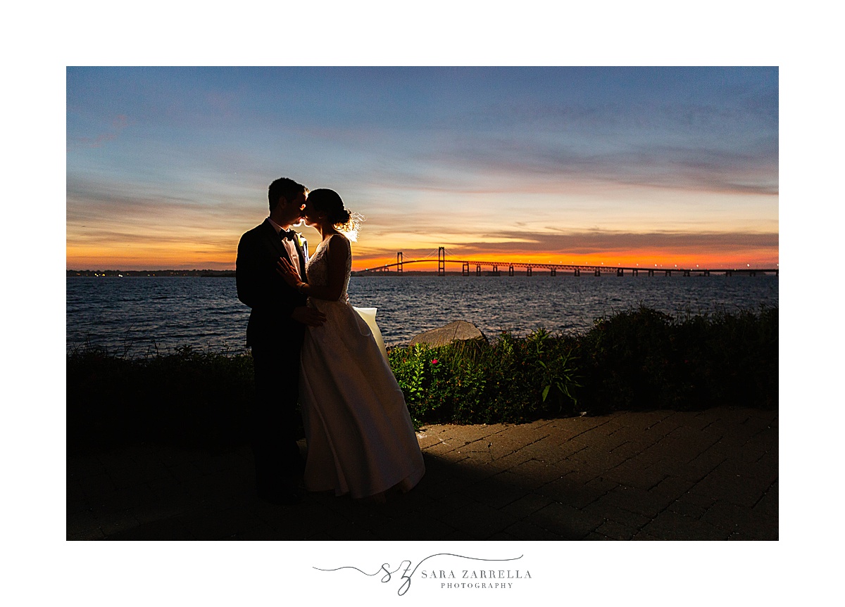 couple kisses at sunset on balcony at Gurney’s Newport Resort