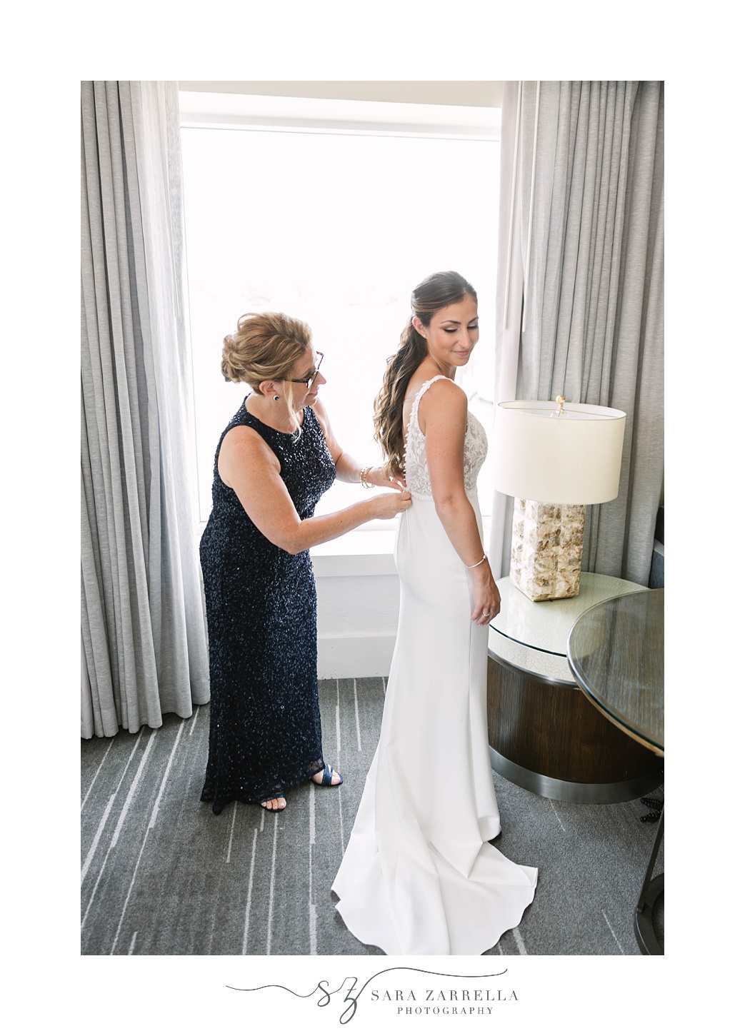 mother helps bride with wedding gown before Gurney’s Newport Resort wedding day