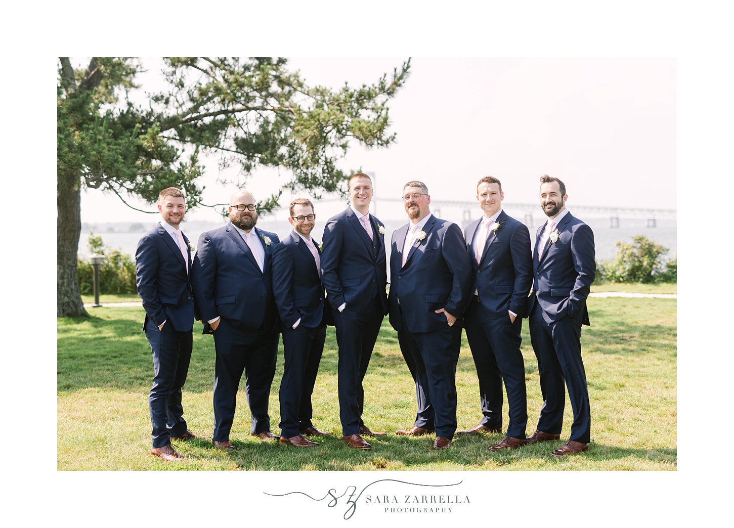 groomsmen in navy suits pose with groom 