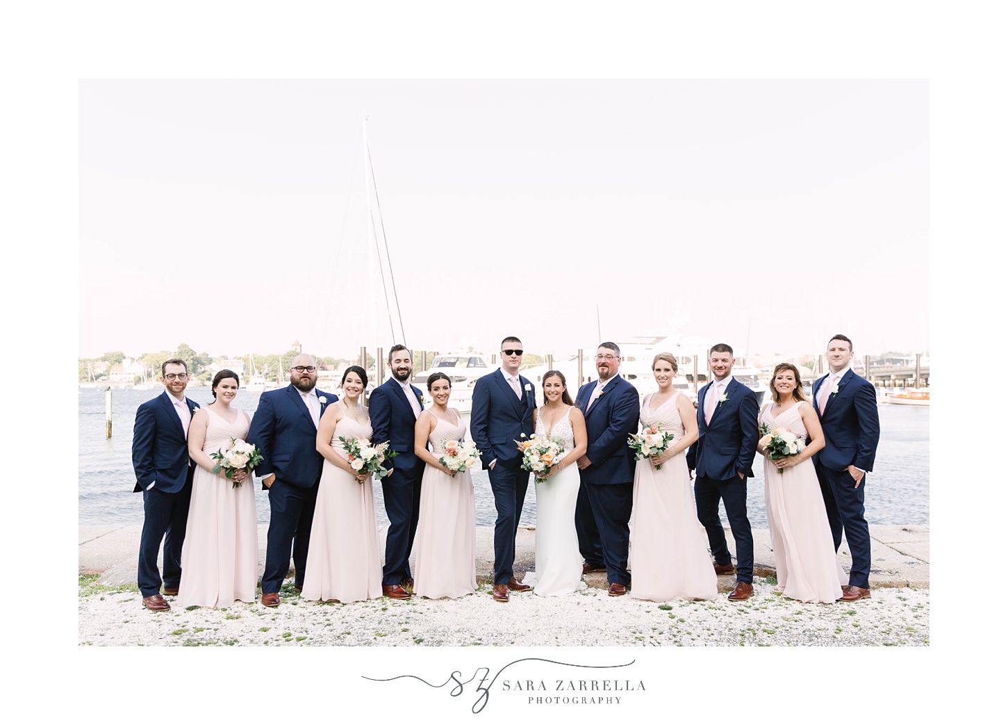 bride and groom pose with bridal party during Gurney’s Newport Resort wedding day