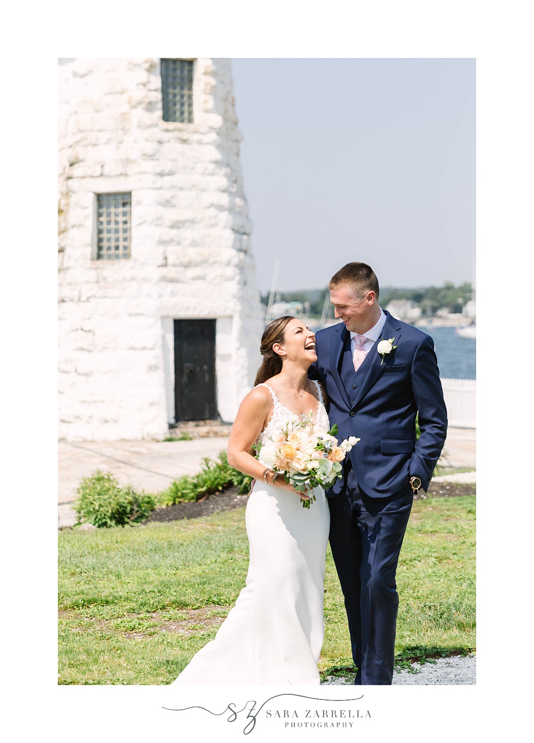 newlyweds laugh by white lighthouse