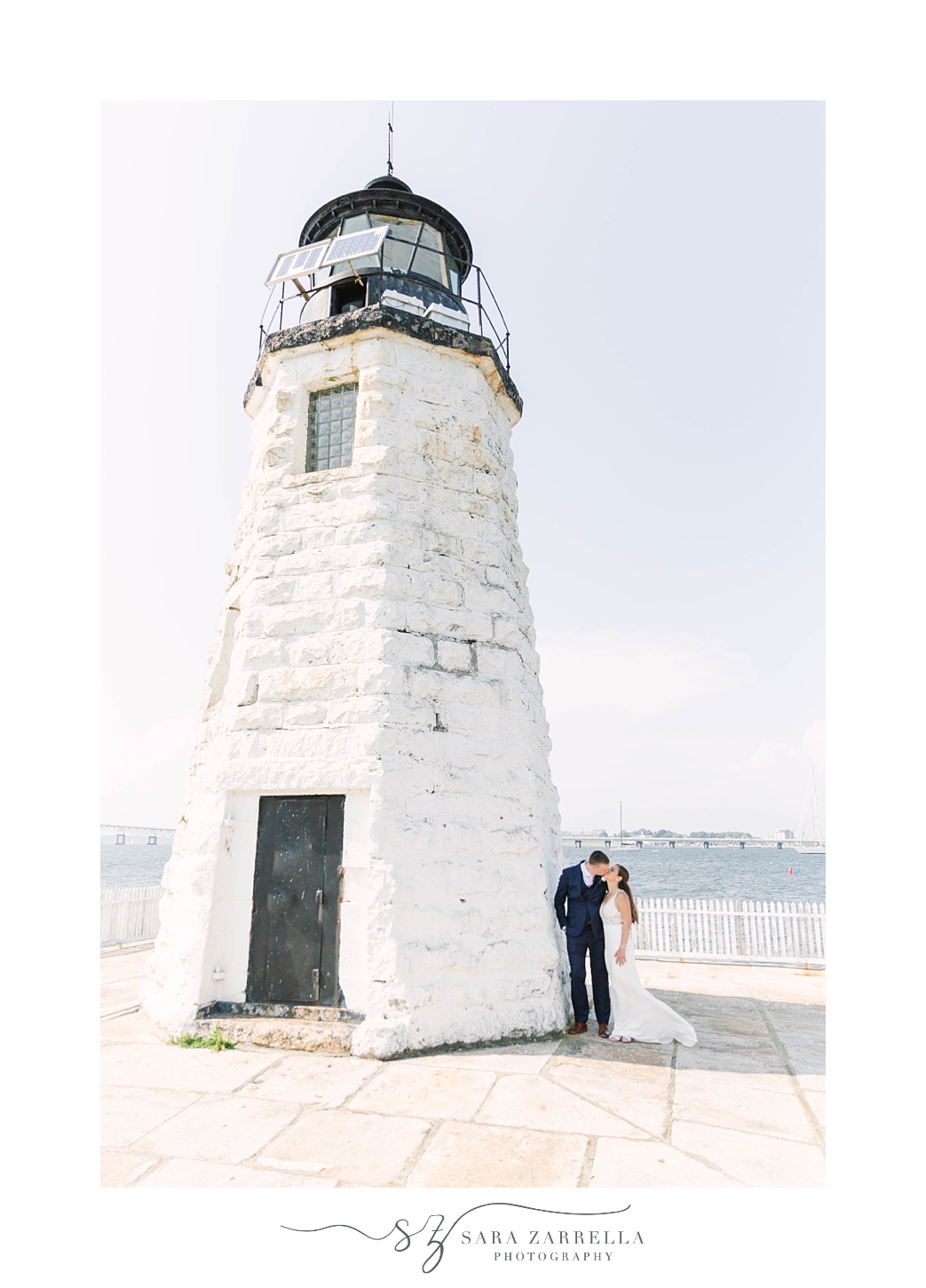 bride and groom kiss by white lighthouse during Gurney’s Newport Resort wedding day