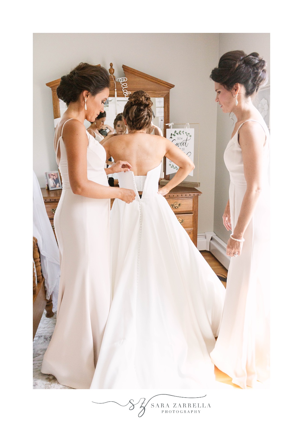 bridesmaids help bride with gown on wedding day