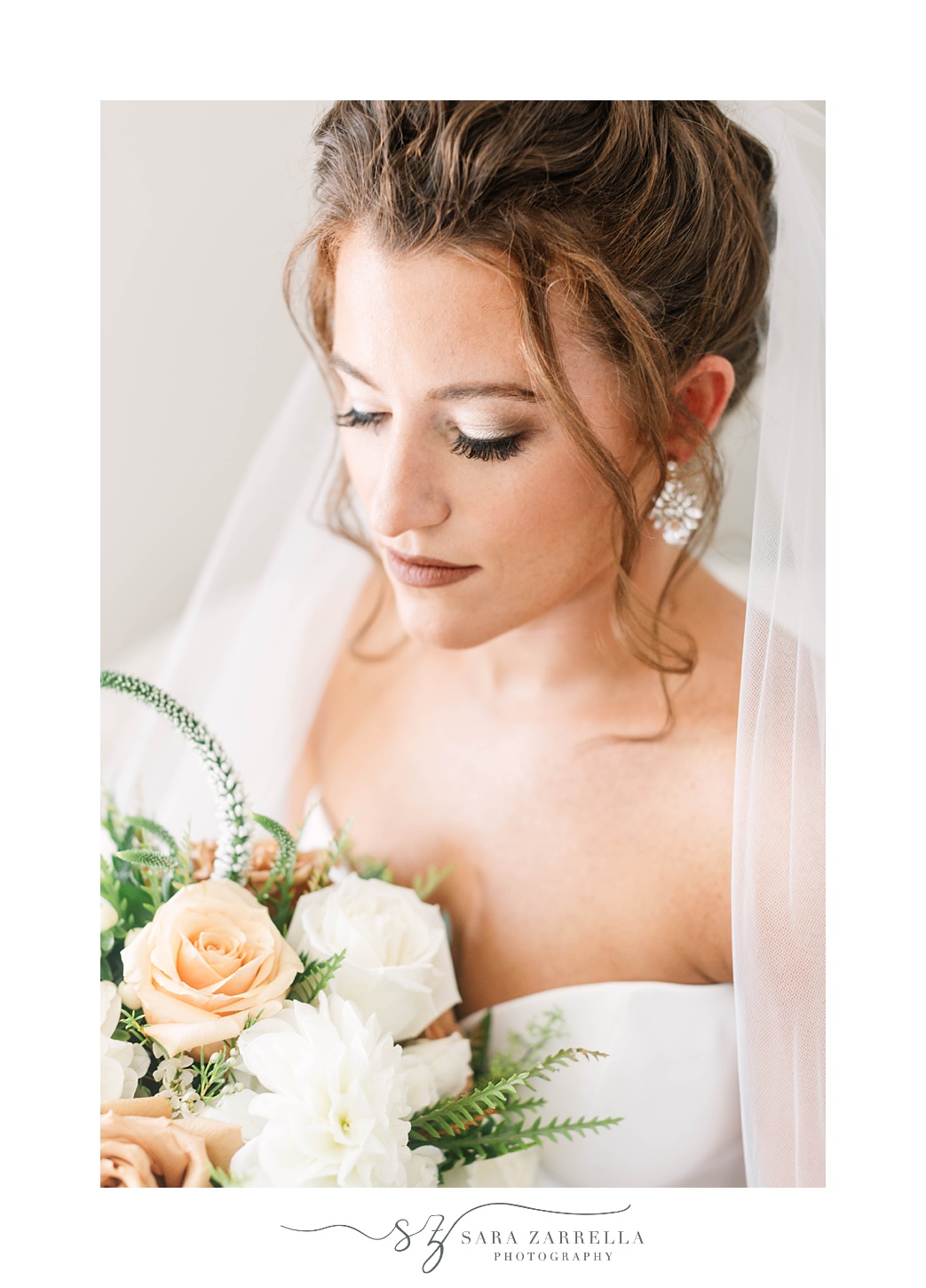 bride looks down at bouquet with peach and white roses