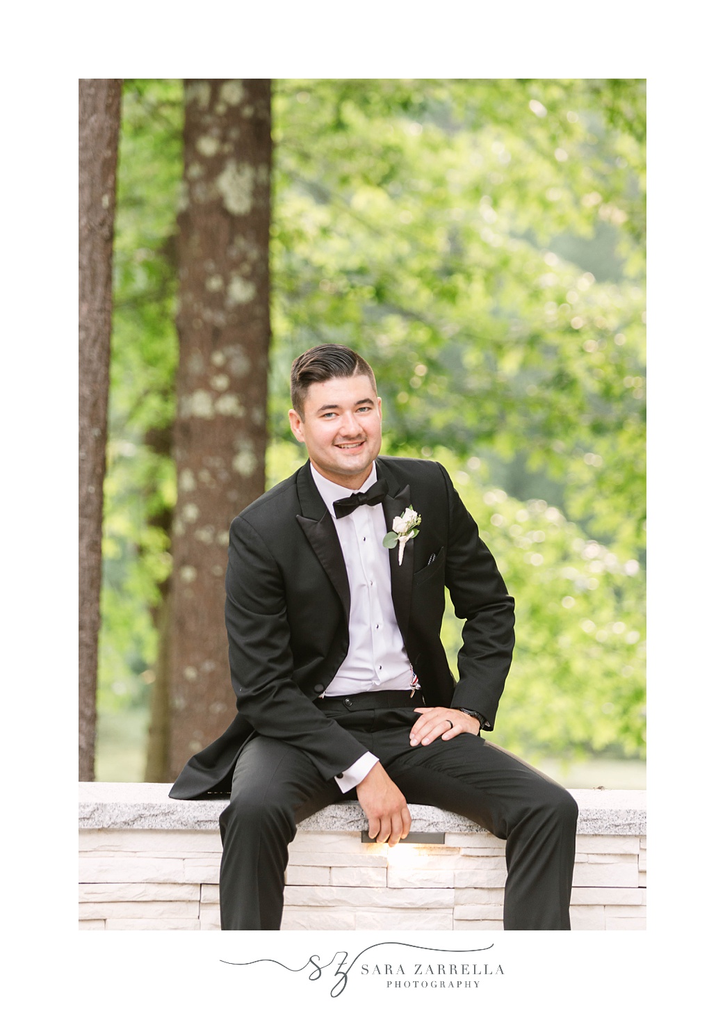 groom sits on wall outside Lakeview Pavilion