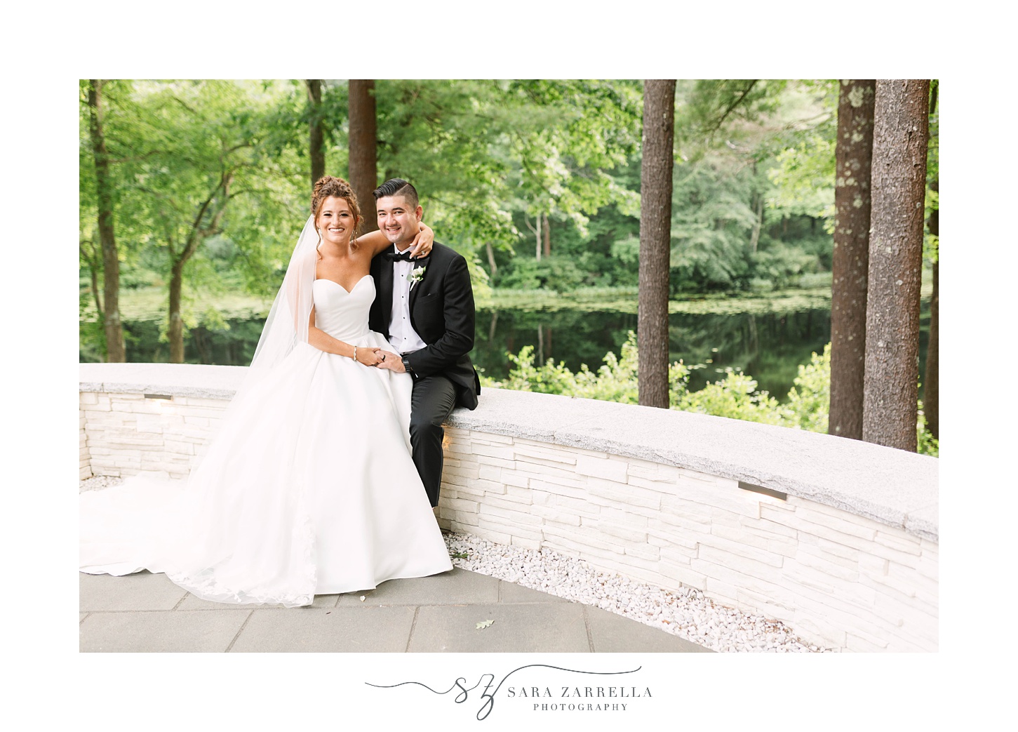 bride and groom sit on brick wall at Lakeview Pavilion