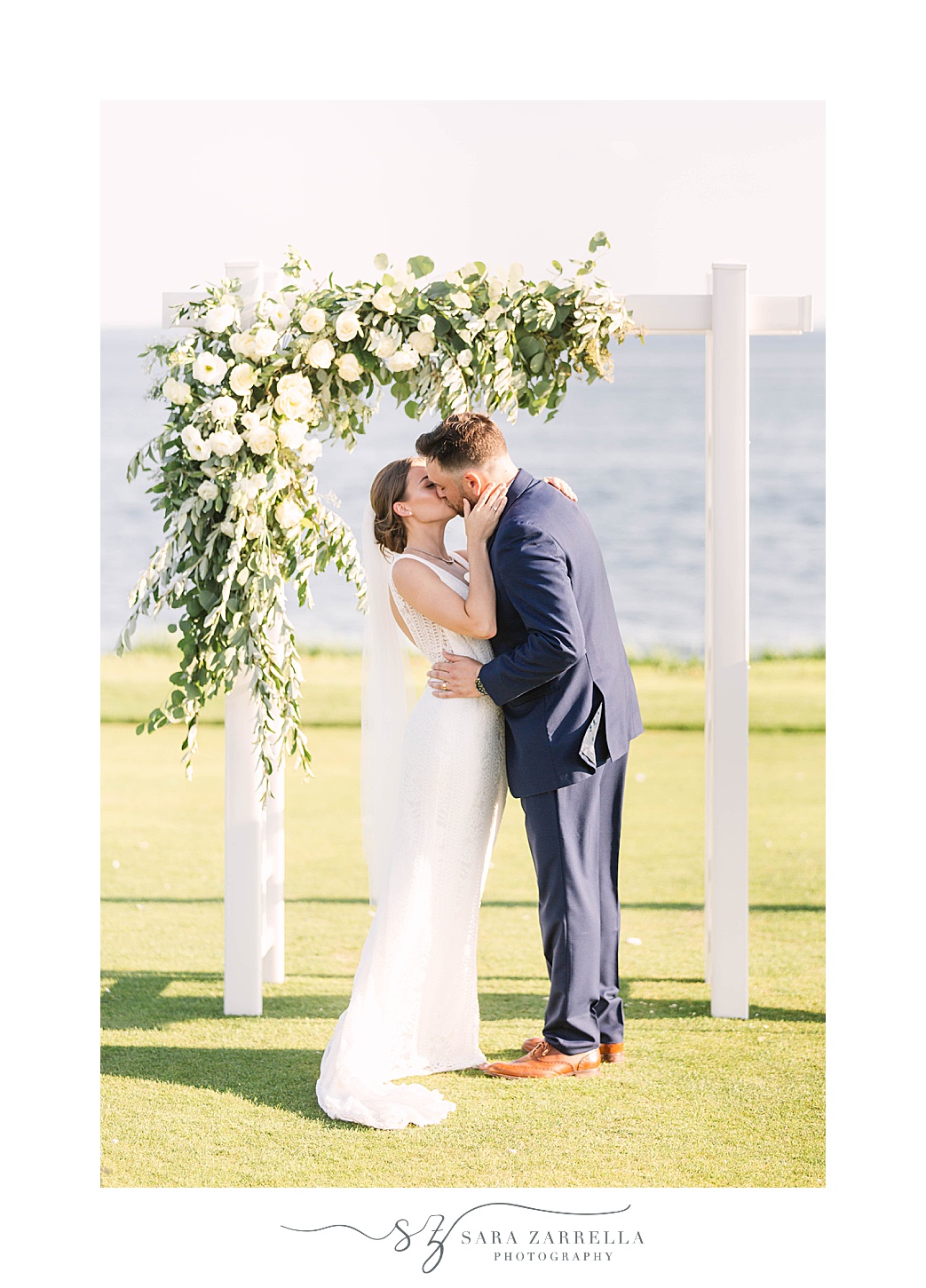 newlyweds kiss under floral arbor at Warwick Country Club