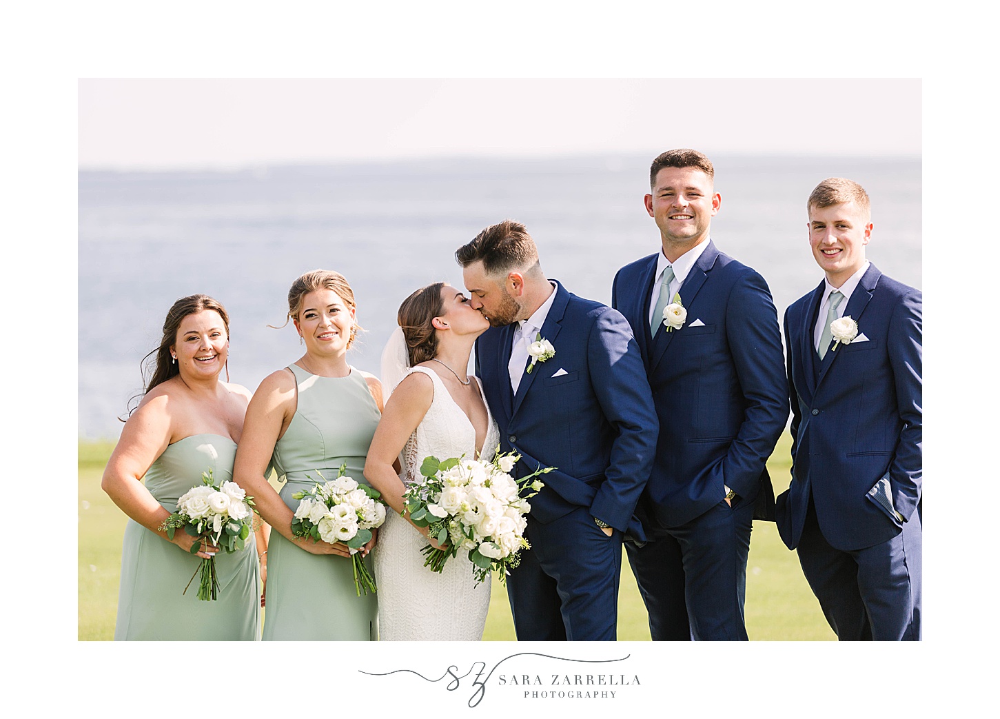 newlyweds kiss while bridal party smiles with them