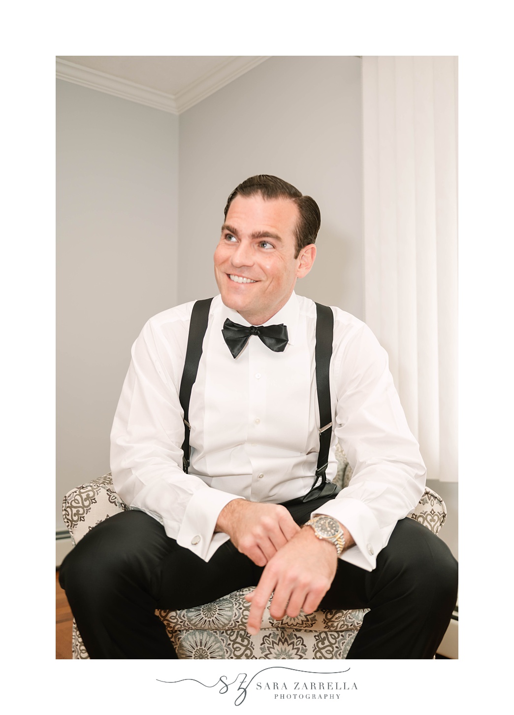 groom sits with bowtie adjusting watch before RI wedding day