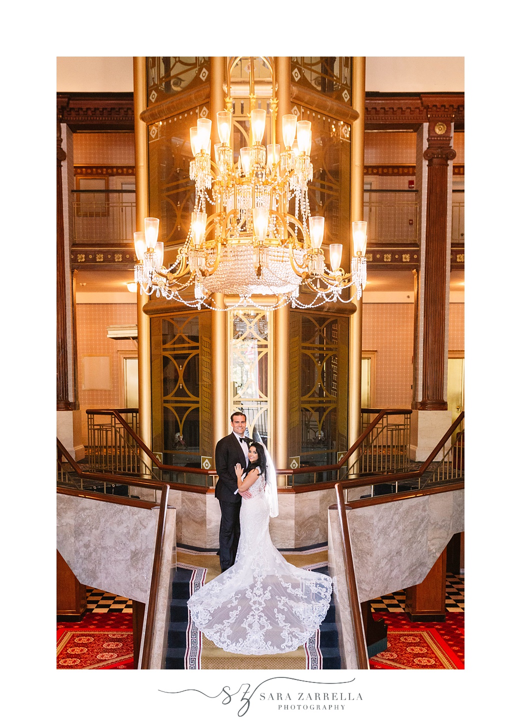 newlyweds pose on grand staircase at  Quidnessett Country Club