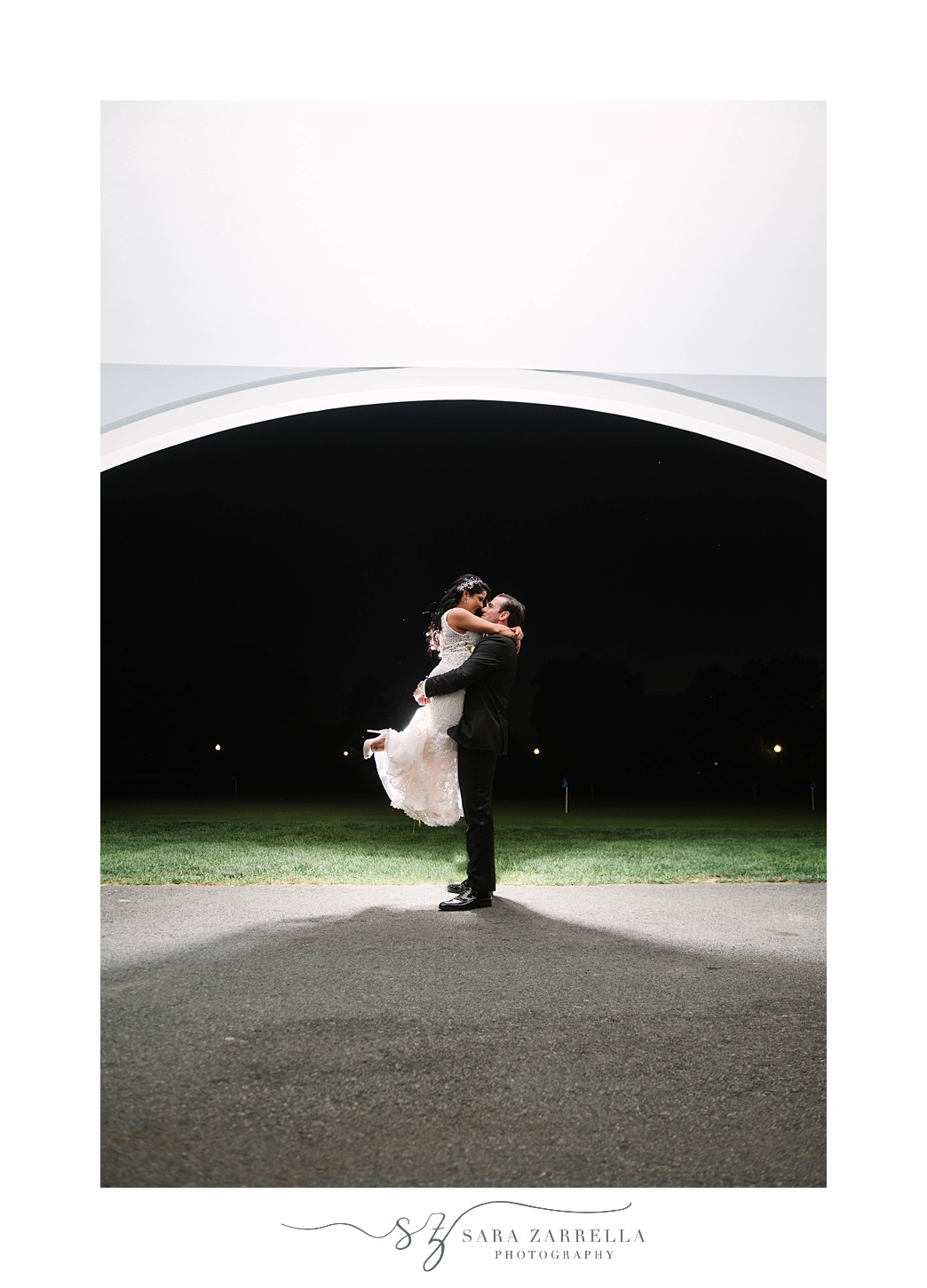 groom lifts bride under arch at Quidnessett Country Club 