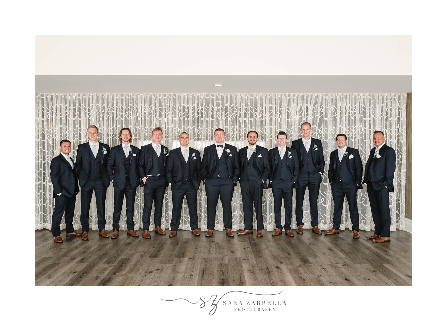 groom and groomsmen pose by detailed wall at Atlantic Resort at Wyndham Newport