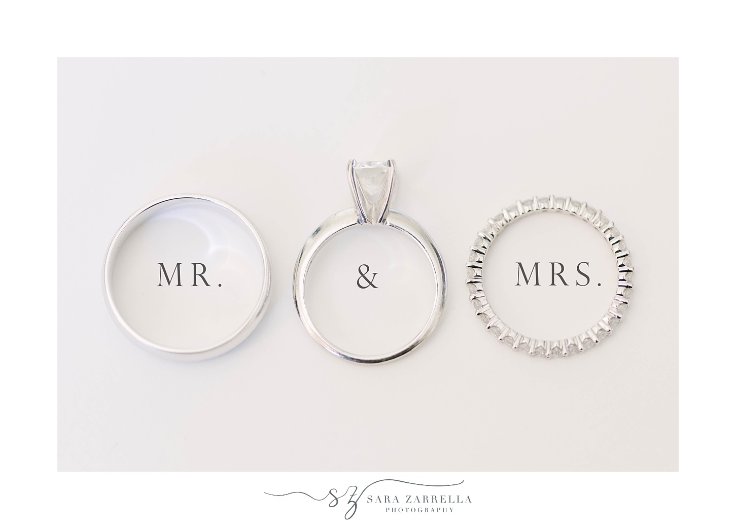 wedding rings lay on white table with Mr. and Mrs. underneath rings