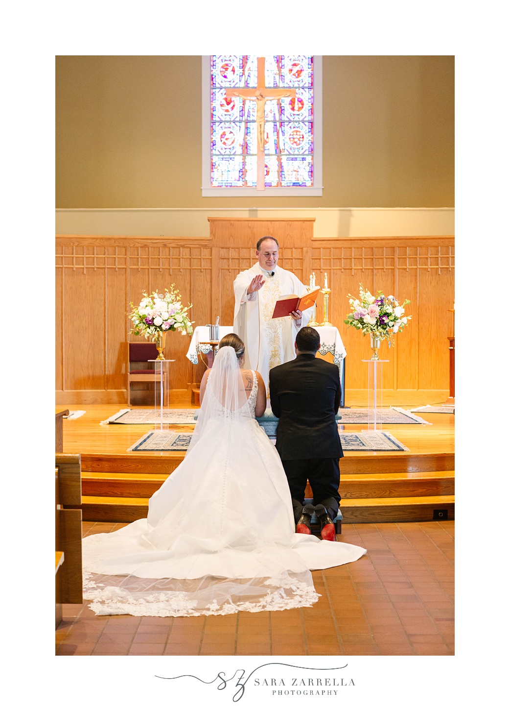 newlyweds kneel at front of church during traditional wedding ceremony in Rhode Island church