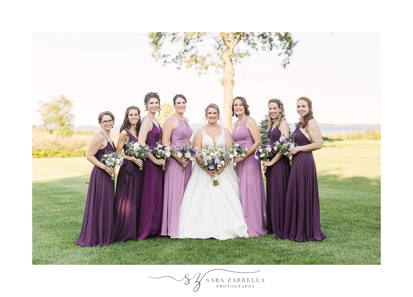 bride stands with bridesmaids in purple gowns