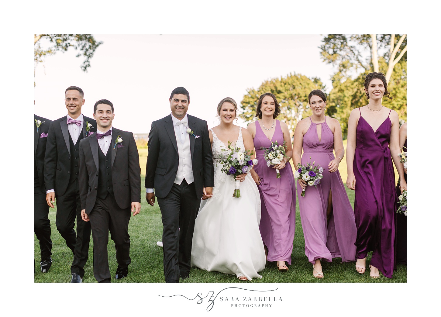 bride and groom walk with wedding party during fall Quidnessett Country Club wedding portraits 