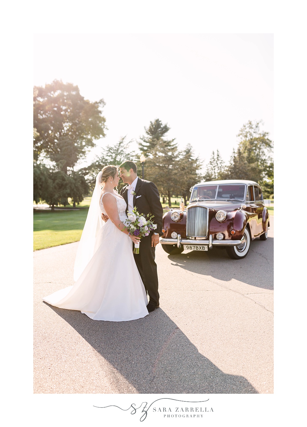 bride and groom kiss by classic car outside Quidnessett Country Club