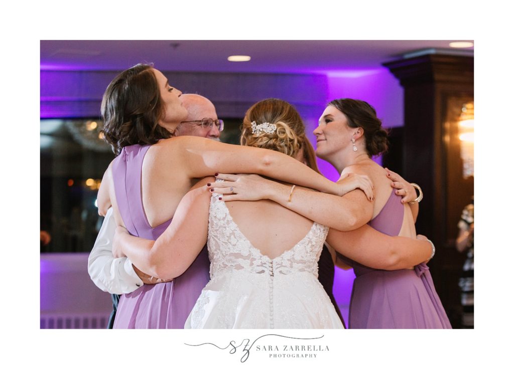 father hugs bride and two sisters during dance at Quidnessett Country Club
