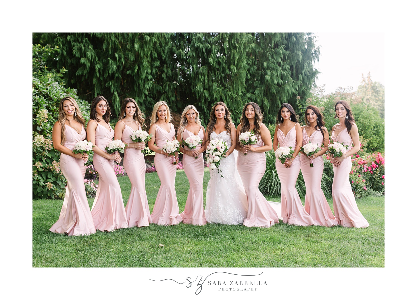 bride poses with bridesmaids in pale pink gowns