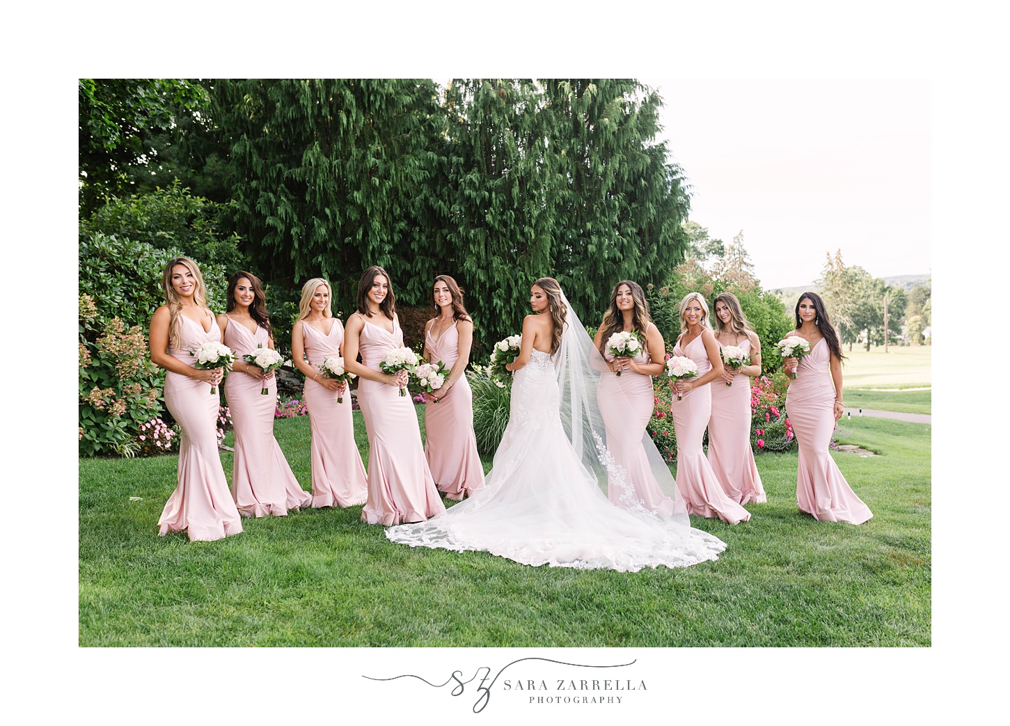 bride poses with bridesmaids in pastel pink gowns 