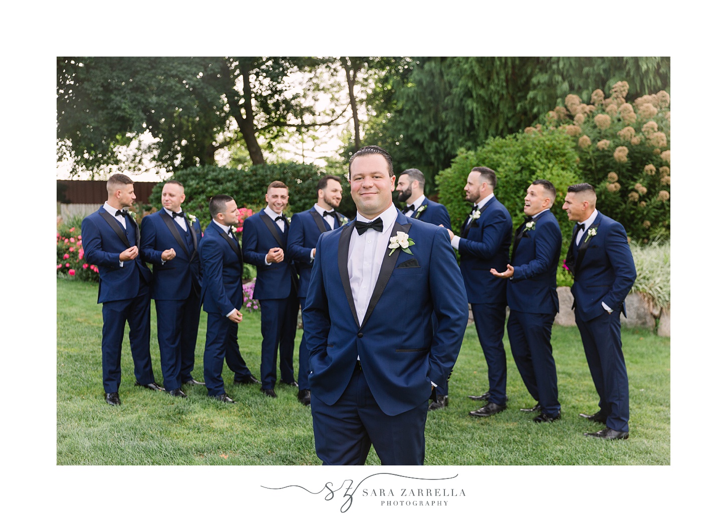 groom stands in front of groomsmen in navy suits