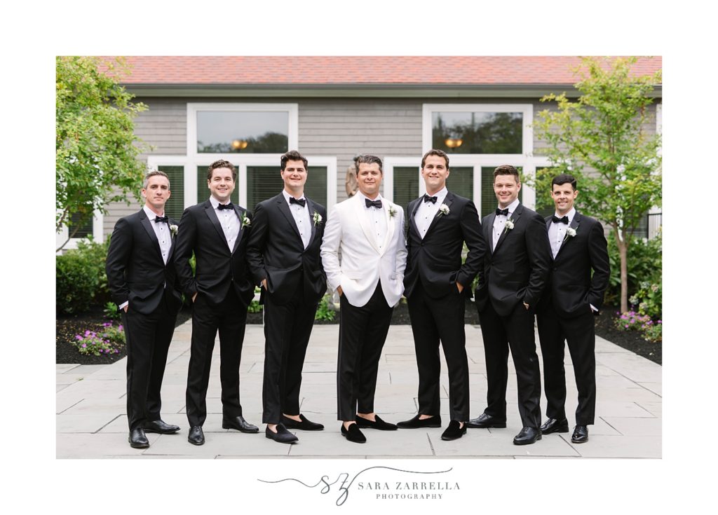 groom in white suit jacket poses with groomsmen 