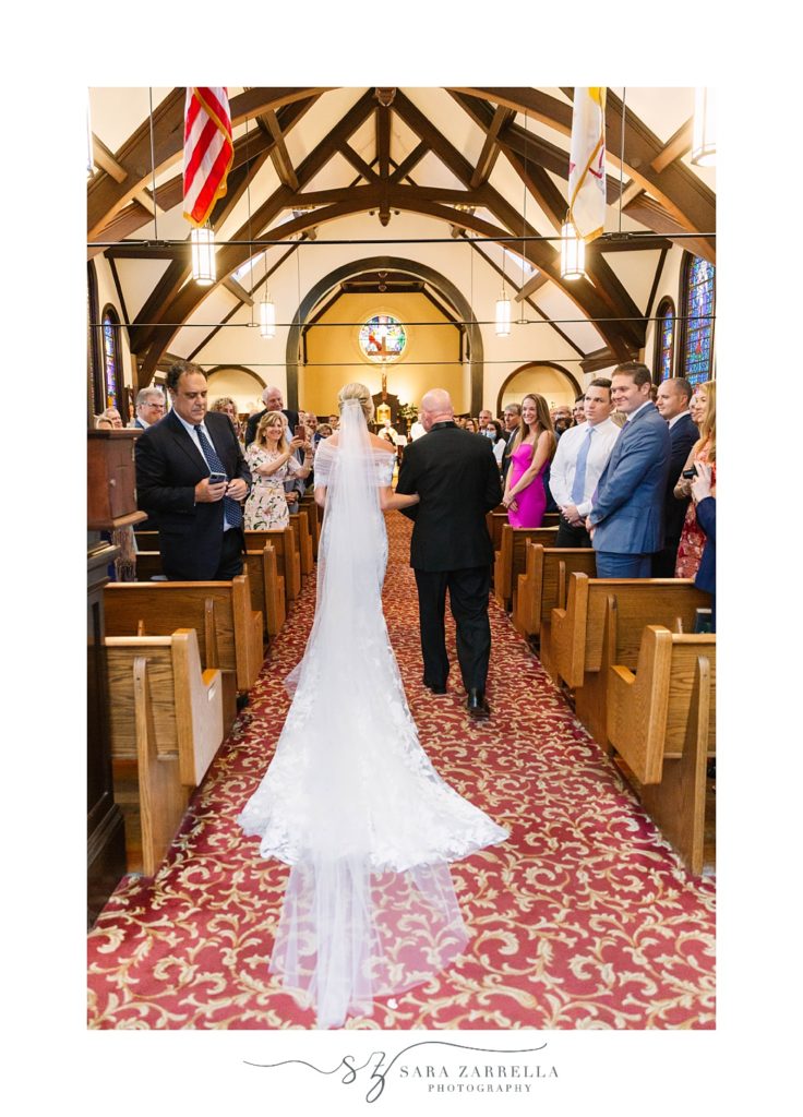 bride walks down the aisle during traditional wedding ceremony in Rhode Island