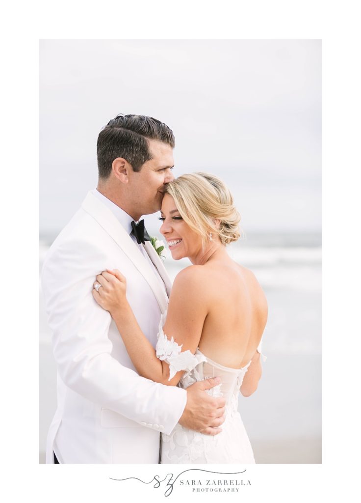 groom hugs bride on the beach during wedding portraits 