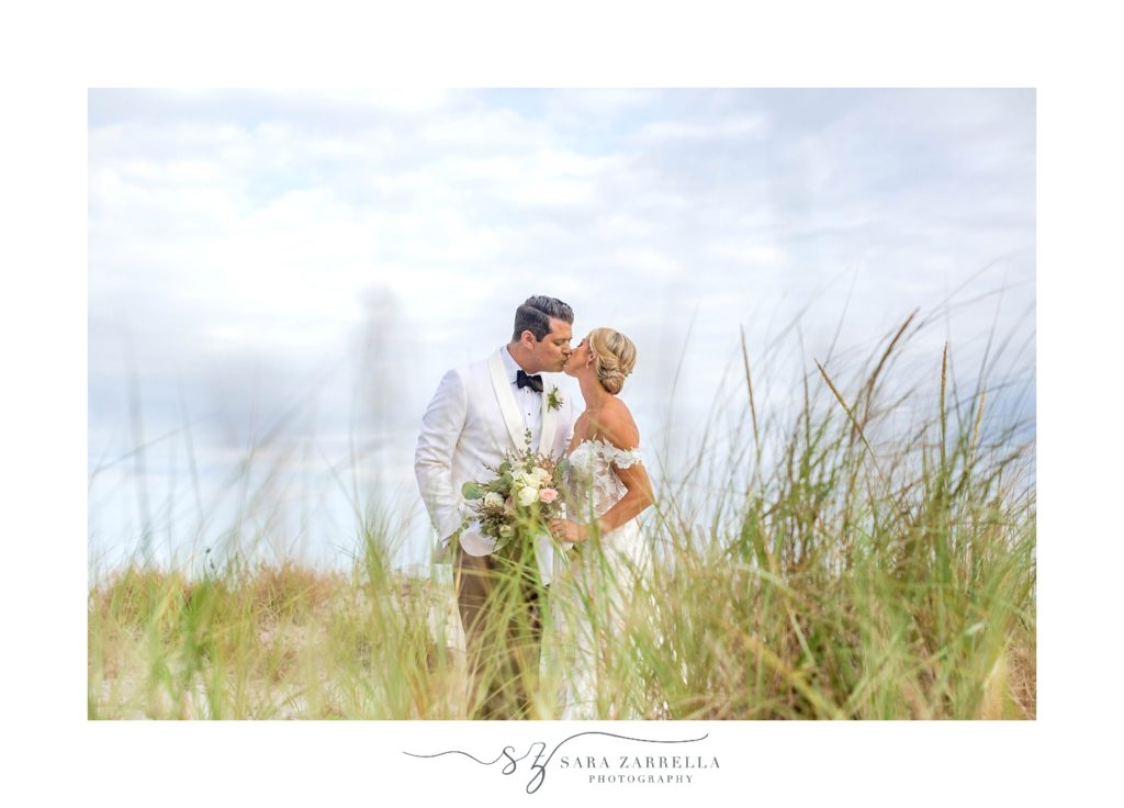 bride and groom kiss through sea grass at Narragansett Bay