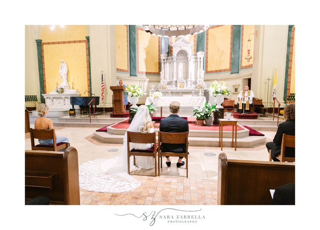 bride and groom sit together during Catholic Church wedding ceremony 