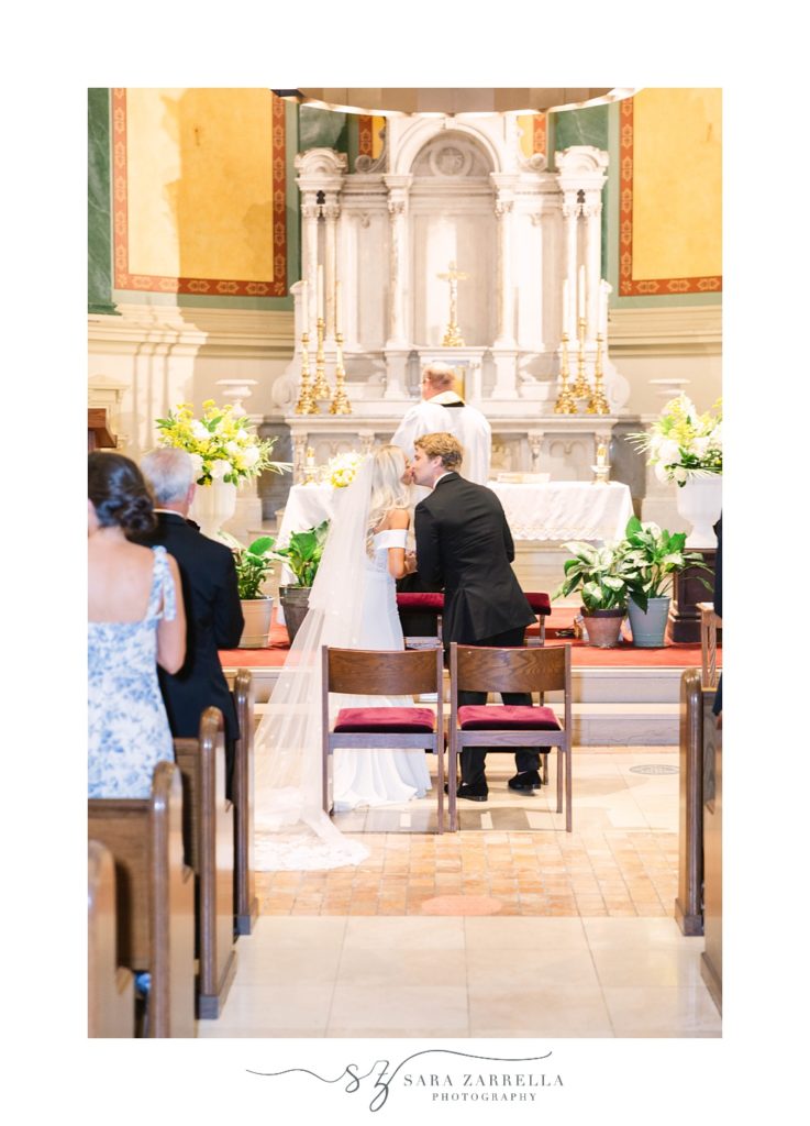 couple kisses during Catholic wedding ceremony in Rhode Island