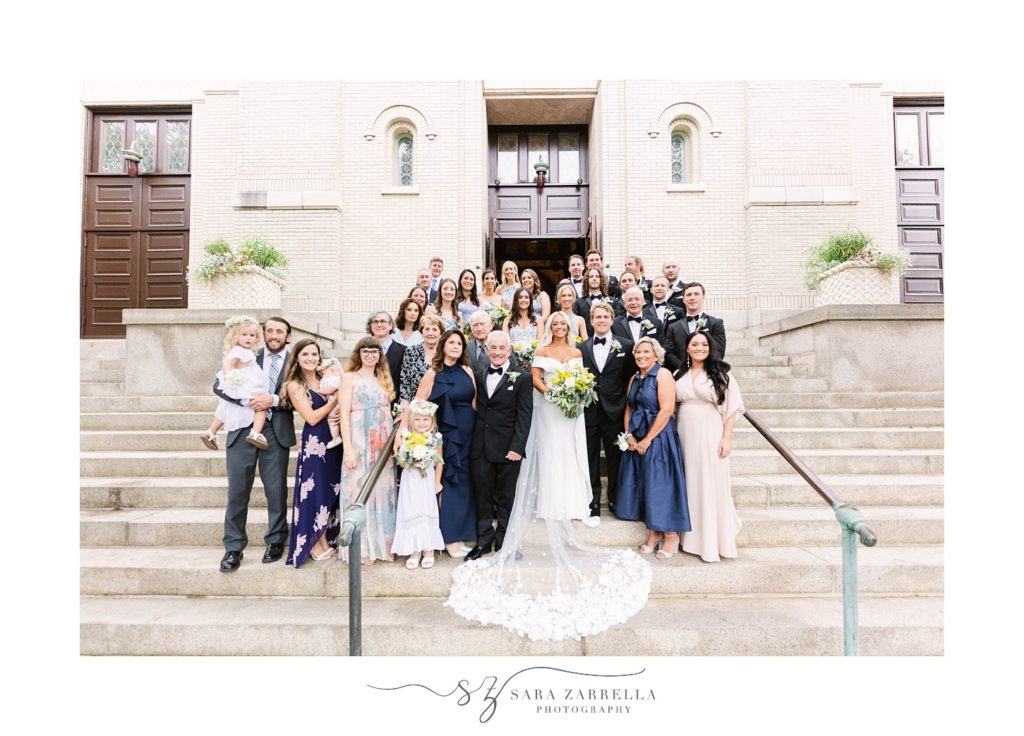 bride and groom pose with wedding guests on steps of Salve Regina chapel 