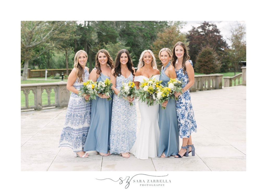 bride stands with bridesmaids in pale blue gowns