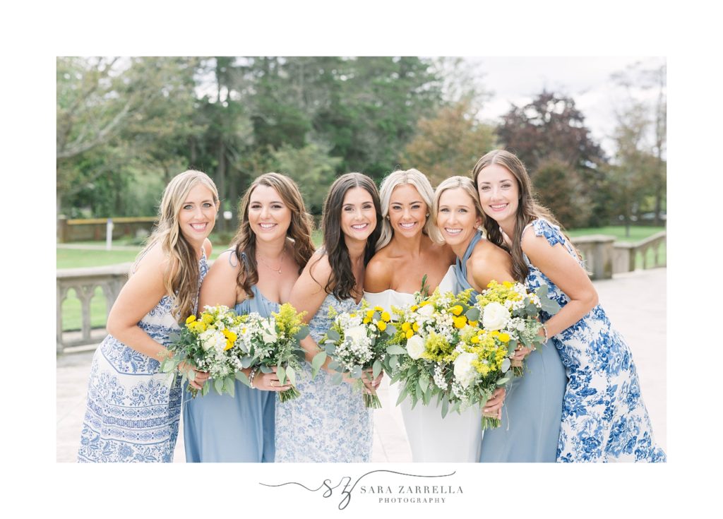 bride and bridesmaids hug closer in mismatched blue and white gowns