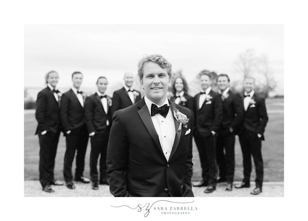 groom poses in front of groomsmen in classic suits 