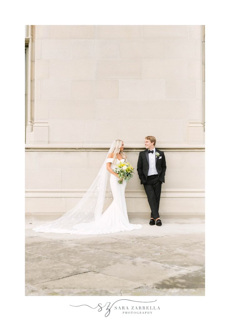 bride and groom lean against wall during Ochre Court wedding portraits 