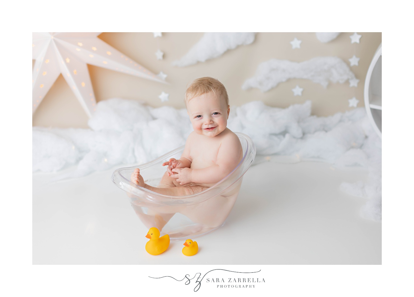 baby plays in tub during cake smash with gold and white decor 